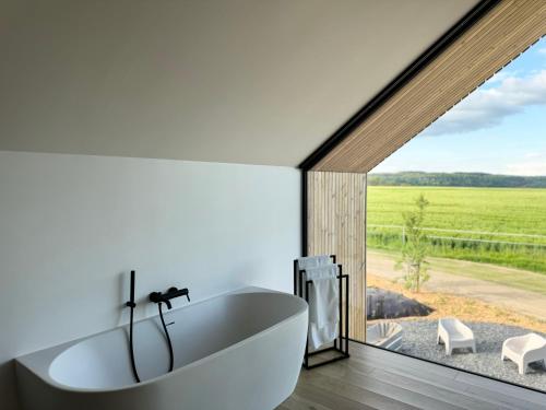 un bagno con vasca bianca e una grande finestra di Durbuy Insolite - Natural Escape a Durbuy