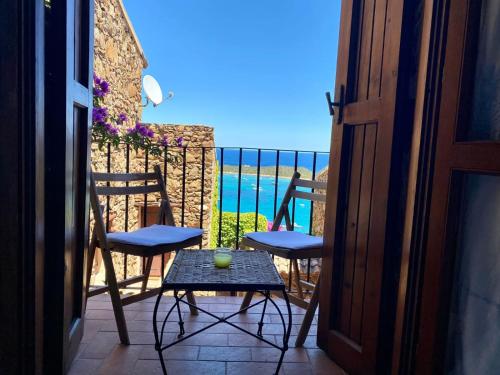 a balcony with chairs and a table and a view of the ocean at Villaggio Est a Capo Coda Cavallo San Teodoro in San Teodoro