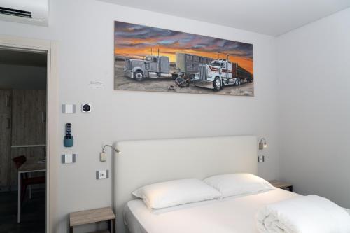 a bedroom with a white bed and a truck on the wall at M-APPHOTEL in Benna