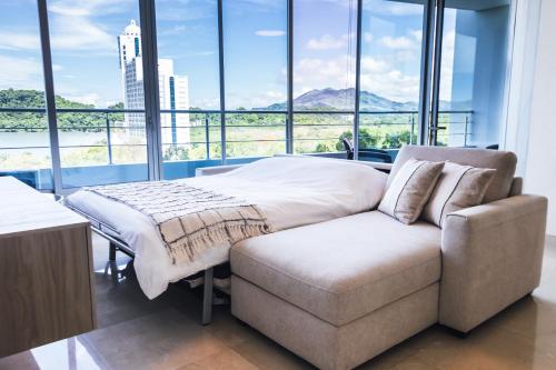 - un lit et un canapé dans une chambre avec fenêtres dans l'établissement Oceanview Apt Near Panama City w/ King Bed & More, à Playa Bonita Village