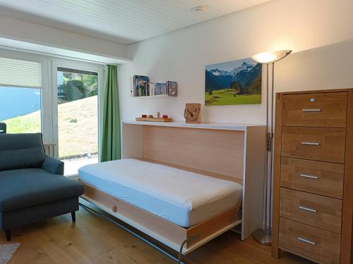 um quarto com uma cama, uma cadeira e uma janela em Berglust em Obermaiselstein