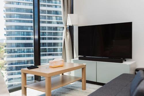 a living room with a television and a coffee table at Modern 2b2b Apt -2 king bed-2 parking-UC-Westfield in Belconnen