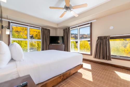 a bedroom with a large white bed and windows at The Peaks Resort and Spa in Telluride