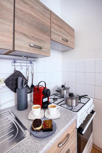 a kitchen counter with two cups of coffee and cookies at Prague - Karlin Apartments in Prague