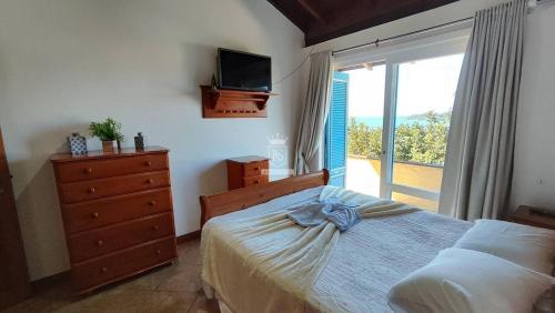 ボンビーニャスにあるA90 - Casa com piscina e linda vista - centro de Bombinhasのベッドルーム(ベッド1台、テレビ、窓付)