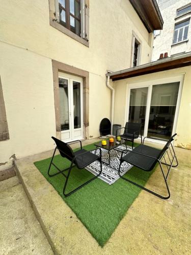 a patio with chairs and a table on grass at Epinal Hyper Centre, Place des Vosges T2 avec terrasse et salon de jardin. in Épinal