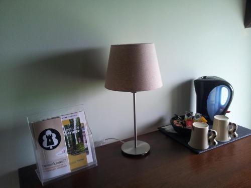 a table with a lamp and a sign on it at B&B Herberg Boerenhol DE MOTE BVBA in Poperinge