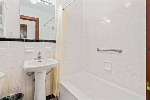 a white bathroom with a sink and a shower at Cavalier by the Sea in Kill Devil Hills