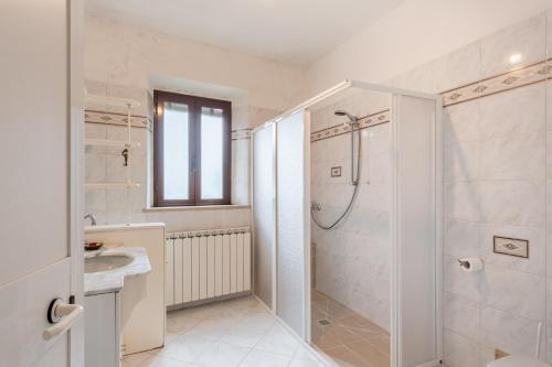 uma casa de banho branca com um chuveiro e um lavatório. em Casa delle Rose em Borgo a Mozzano