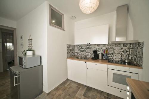  La cuisine est équipée de placards blancs et d'un réfrigérateur. dans l'établissement Sosiego Insolite Jacuzzi ParkingFree 5min Centre, à Mulhouse