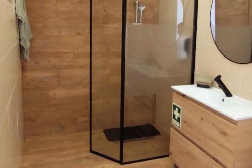 una ducha con una puerta de cristal junto a un lavabo en A Nossa Estrela nº7, en Póvoa de São Miguel