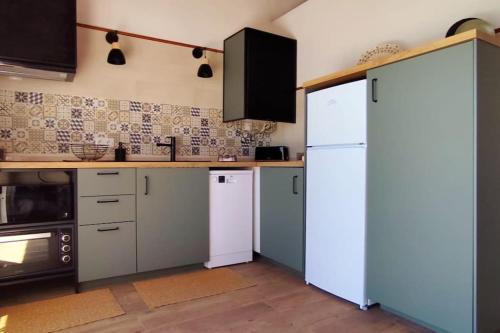 a kitchen with a white refrigerator and a stove at A Nossa Estrela nº7 in Póvoa de São Miguel
