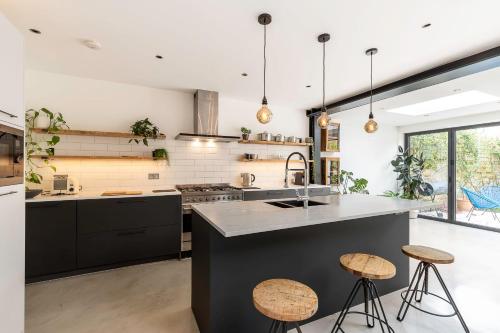 倫敦的住宿－Spacious and Charming Brixton Home，厨房配有黑色橱柜和带凳子的台面