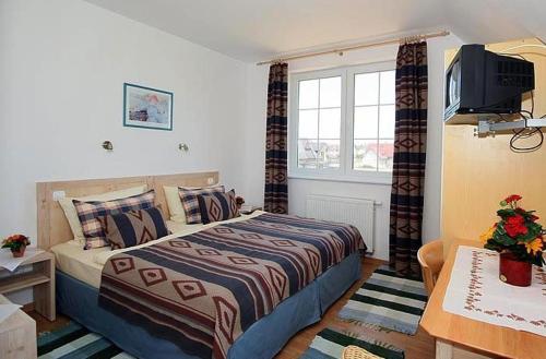 a hotel room with a bed and a television at Dworek Łeba i Domki Ranczo Itrich in Łeba