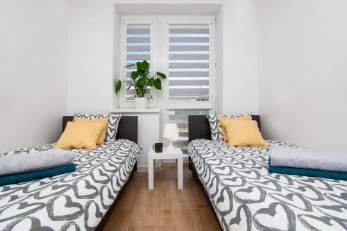 two beds in a room with a window at Modern Apartament Chełm 2 sypialnie in Chełm