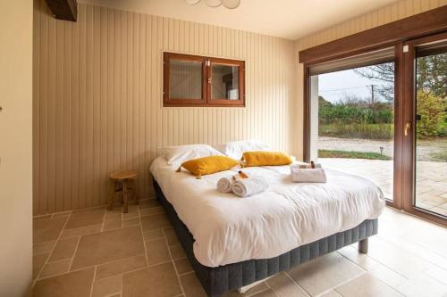 une chambre avec un grand lit avec des serviettes dessus dans l'établissement Maison famille-10 min Deauville, à Saint-Étienne-la-Thillaye