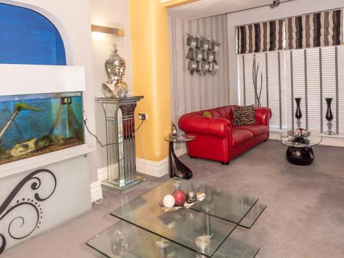 a living room with a red couch and a fish tank at The Kenley Hotel in Blackpool