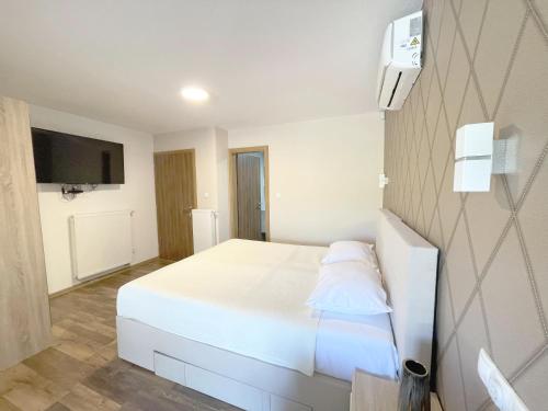 a bedroom with a white bed and a tv at Villa Sarajevo in Vareš