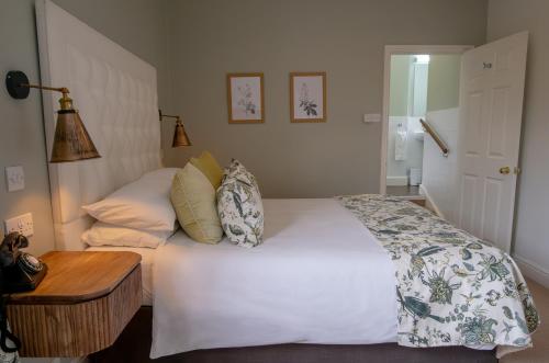 a bedroom with a white bed and a wooden table at Leeds Castle Stable Courtyard Bed and Breakfast in Maidstone