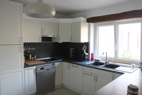 una cucina con armadi bianchi, lavandino e finestra di Agréable maison de ville de 120m² à Villejust a Villejust