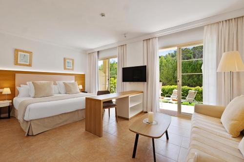 a hotel room with a bed and a desk at VIVA Cala Mesquida Suites & Spa Adults Only 16 in Cala Mesquida