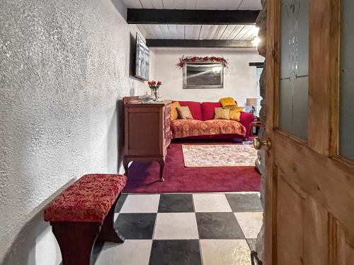 een woonkamer met een rode bank en een geruite vloer bij Lyndene Cottage in Moel-tryfan