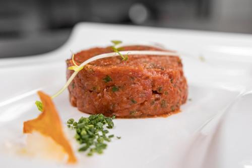 a white plate with a piece of meat on it at Hotel Baer & Post Zernez in Zernez