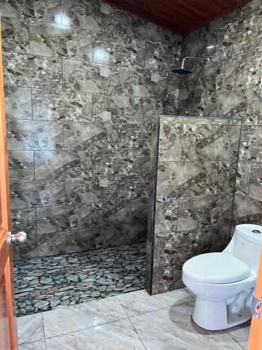 a bathroom with a toilet and a stone wall at Vistaverde Lodge in Monteverde Costa Rica