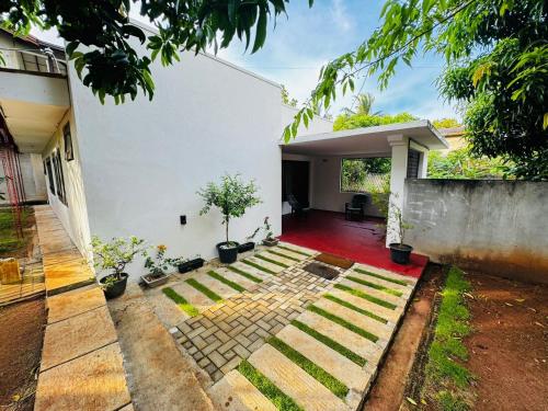 a white house with a red floor and a yard at Prestiva Stay in Anuradhapura
