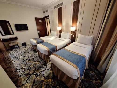 a hotel room with three beds and a television at فندق منار الإيمان in Medina