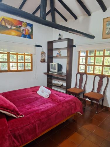Un dormitorio con una cama roja y dos sillas. en Refugio Villa Tere, en Villa de Leyva