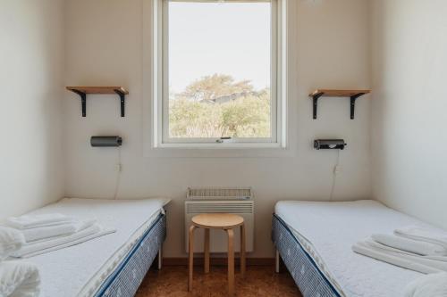 two beds in a room with a window at Vallersviks Vandrarhem Änggården in Frillesås