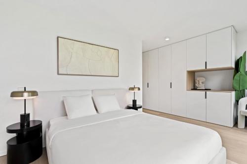 een witte slaapkamer met een groot wit bed en witte kasten bij Chic 80sqm Luxe Apt - Heart of Luxembourg City in Luxemburg