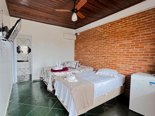 a bedroom with two beds and a brick wall at Pousada Maravista in Cananéia