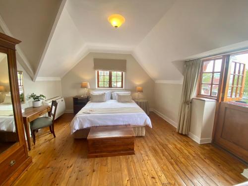 a bedroom with a bed and a desk and windows at Acorn House in Cape Town