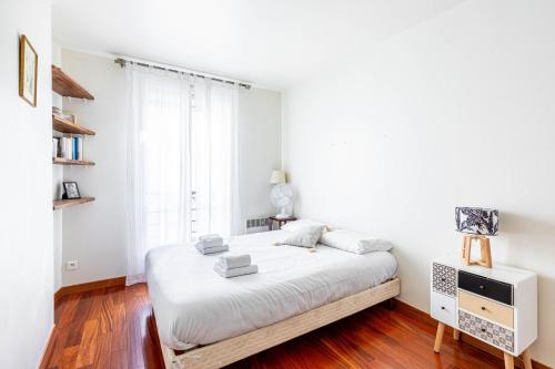 une chambre blanche avec un lit et une fenêtre dans l'établissement GuestReady - Bright retreat near Belleville, à Paris