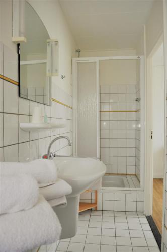 a white bathroom with a sink and a shower at Hotel de Greune Weide in Eibergen