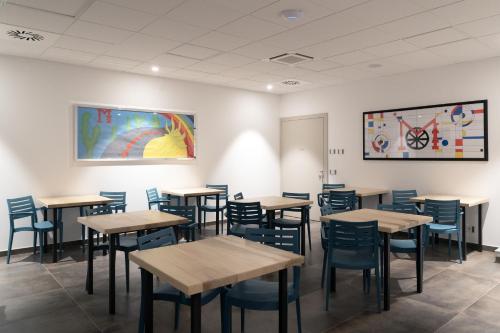 a dining room with tables and chairs and a painting at M-APPHOTEL in Benna