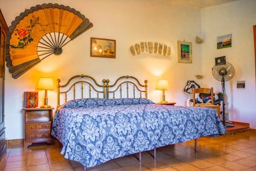 Schlafzimmer mit einem Bett mit blauer Bettdecke und einem Ventilator in der Unterkunft Villa La Voce Del Vento in Pastena
