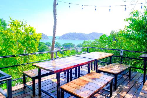 a table and benches on a deck with a view of the water at Woodcookies Guesthouse in Pangkor