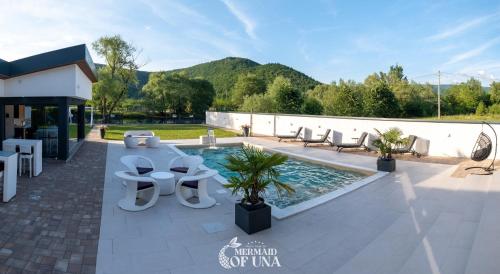 a patio with a pool and chairs and a building at Villa Mermaid of Una in Bihać