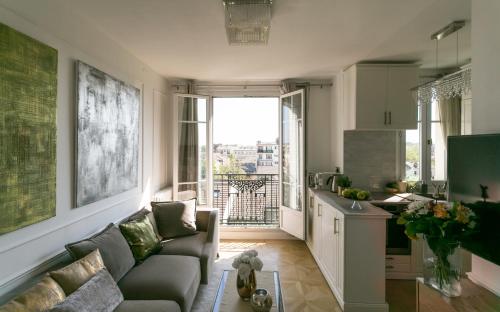 un salon avec un canapé et une cuisine dans l'établissement Appartement de charme près de La Défense, à Colombes