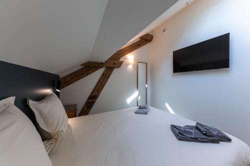 a bedroom with a white bed and a flat screen tv at Hôtel du DOMAINE SAINT LOUP in Michelbach