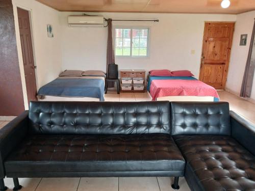 a living room with two beds and a leather couch at Hotel Cabañas Casita La Ermita in San Carlos