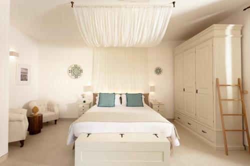 a white bedroom with a large bed with blue pillows at Borgo Mulino a Vento - Resort in Uggiano la Chiesa
