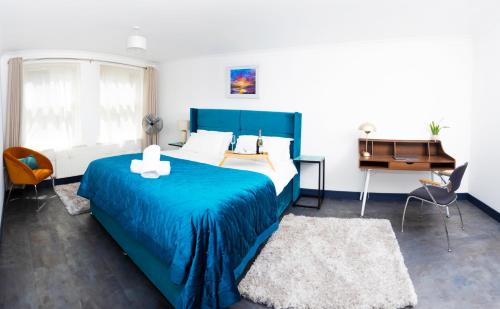 a bedroom with a blue bed and a desk at Ramsgate Boutique Apartment in Ramsgate
