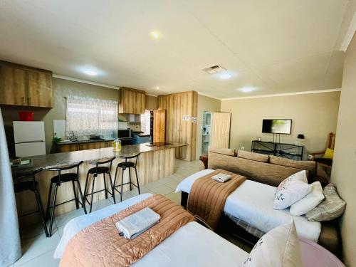 a living room with two beds and a kitchen at Ivanka's Self-Catering Flat in Kimberley