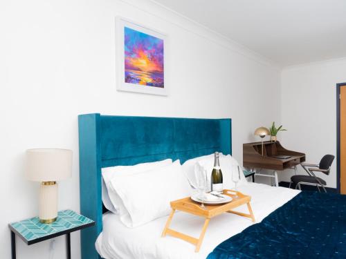 a bedroom with a bed with a blue headboard and a table at Ramsgate Boutique Apartment in Ramsgate