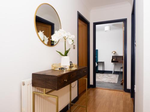 a hallway with a mirror and a vase with flowers at Ramsgate Boutique Apartment in Ramsgate