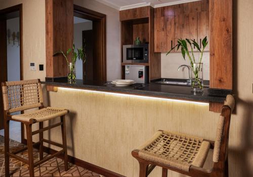 cocina con barra con 2 sillas y barra en فندق ايليت الهجرة en Medina